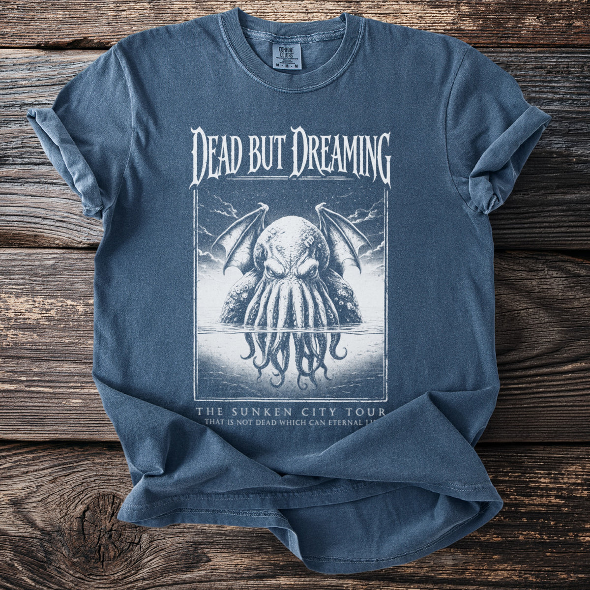 Blue t-shirt with "Dead But Dreaming" and tentacled creature graphic and tour text.