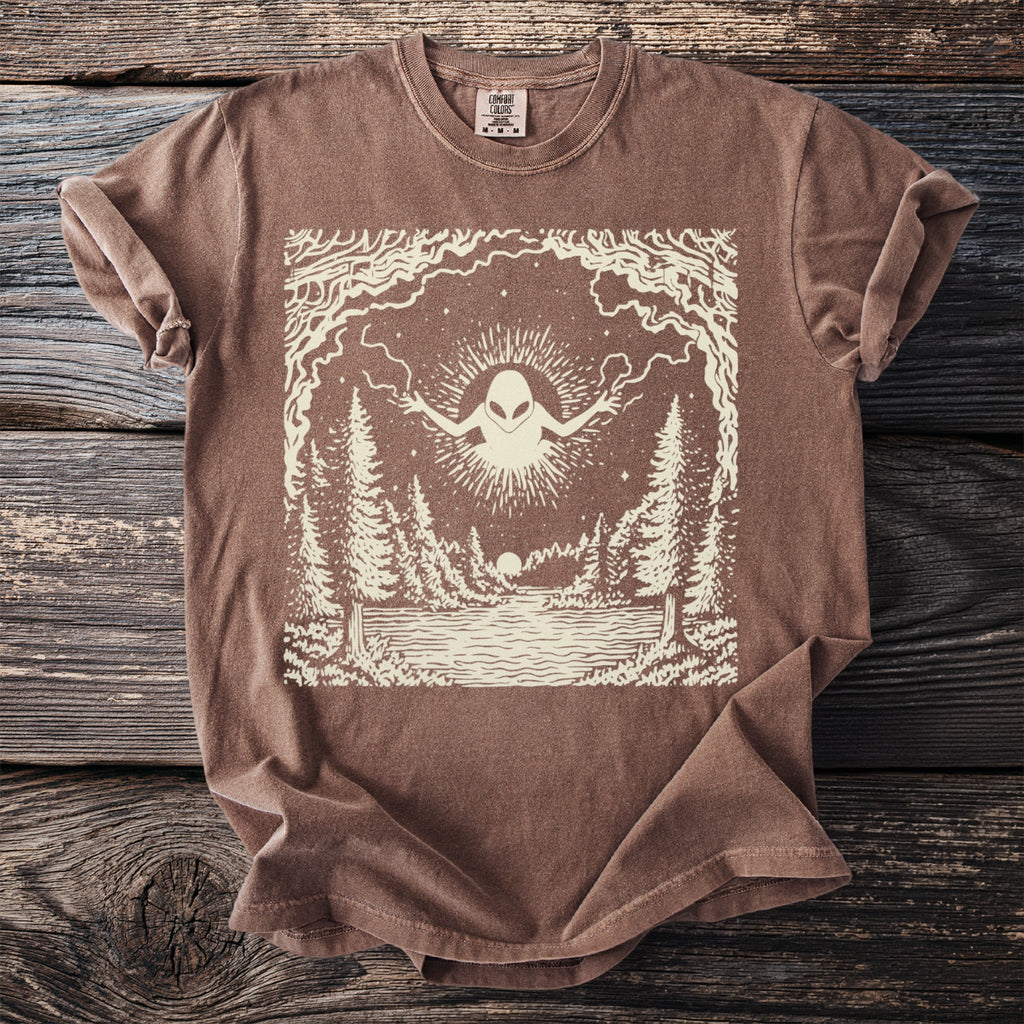 T-shirt with an alien design over a forest and lake scene.