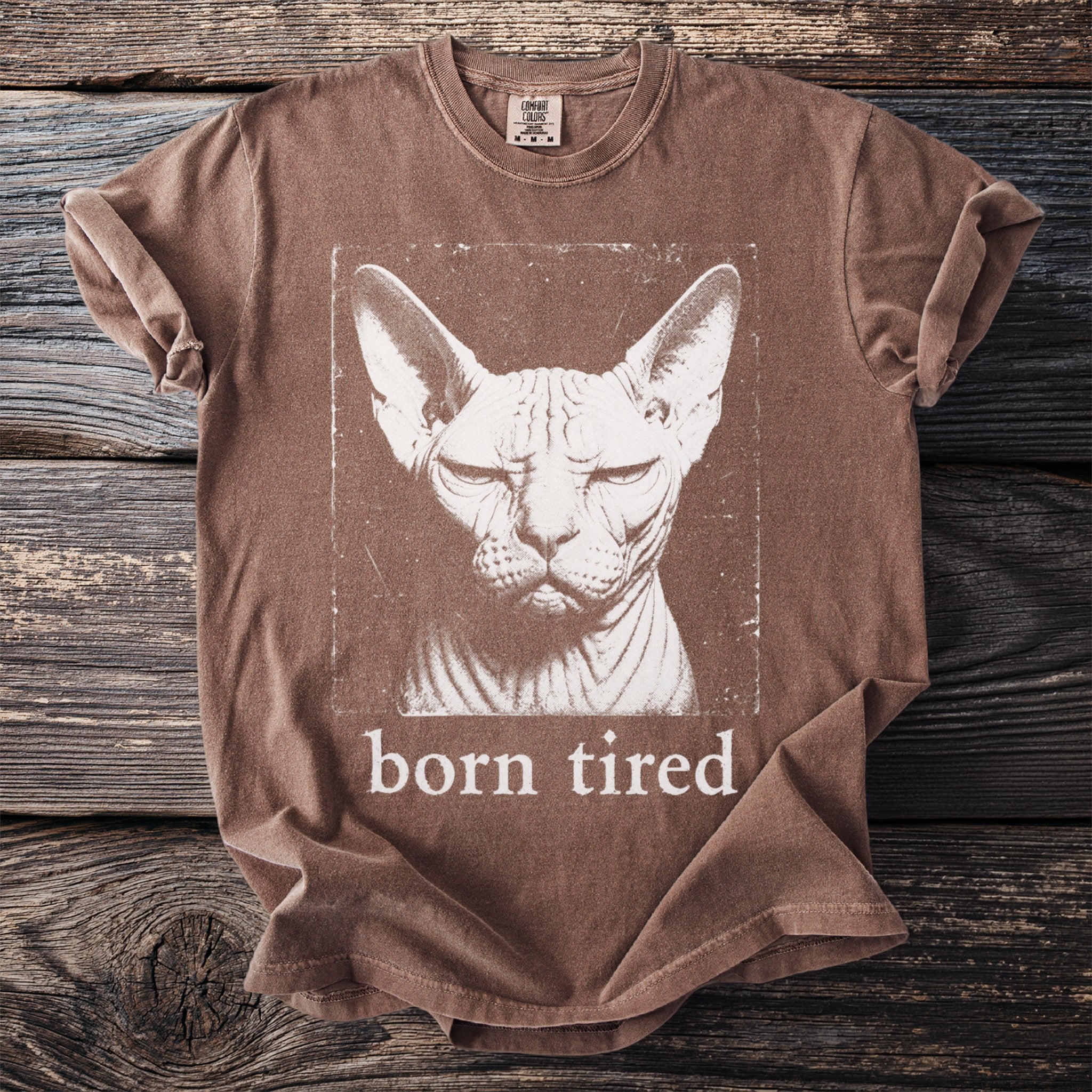 Brown t-shirt with a distressed print of a Sphynx cat and text "born tired".