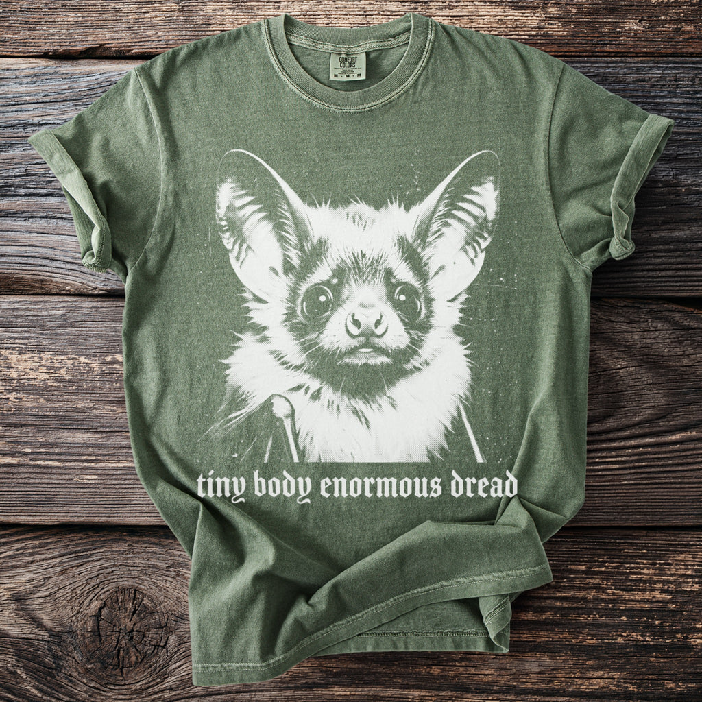 Green t-shirt with white graphic of a bat and text that reads "tiny body enormous dread".