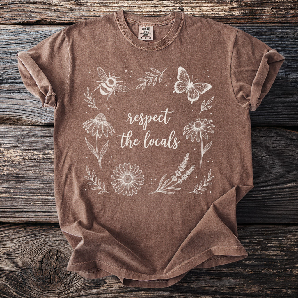 Brown t-shirt with white line art butterfly, bee, flowers, and text "respect the locals".