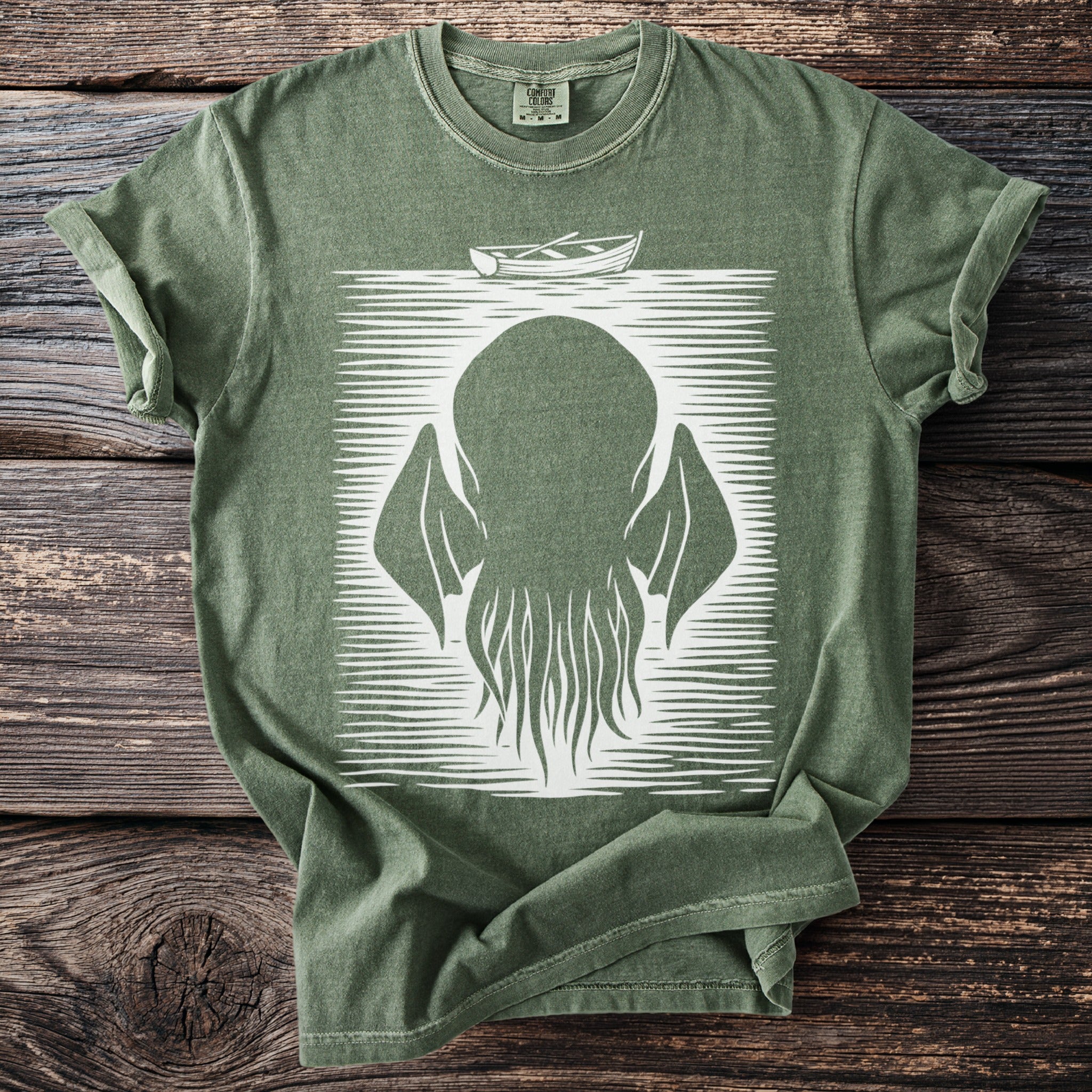 Green t-shirt with a white graphic of a boat over a creature with tentacles.