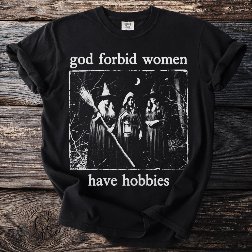 Black t-shirt with "god forbid women have hobbies" text and three witch illustration.
