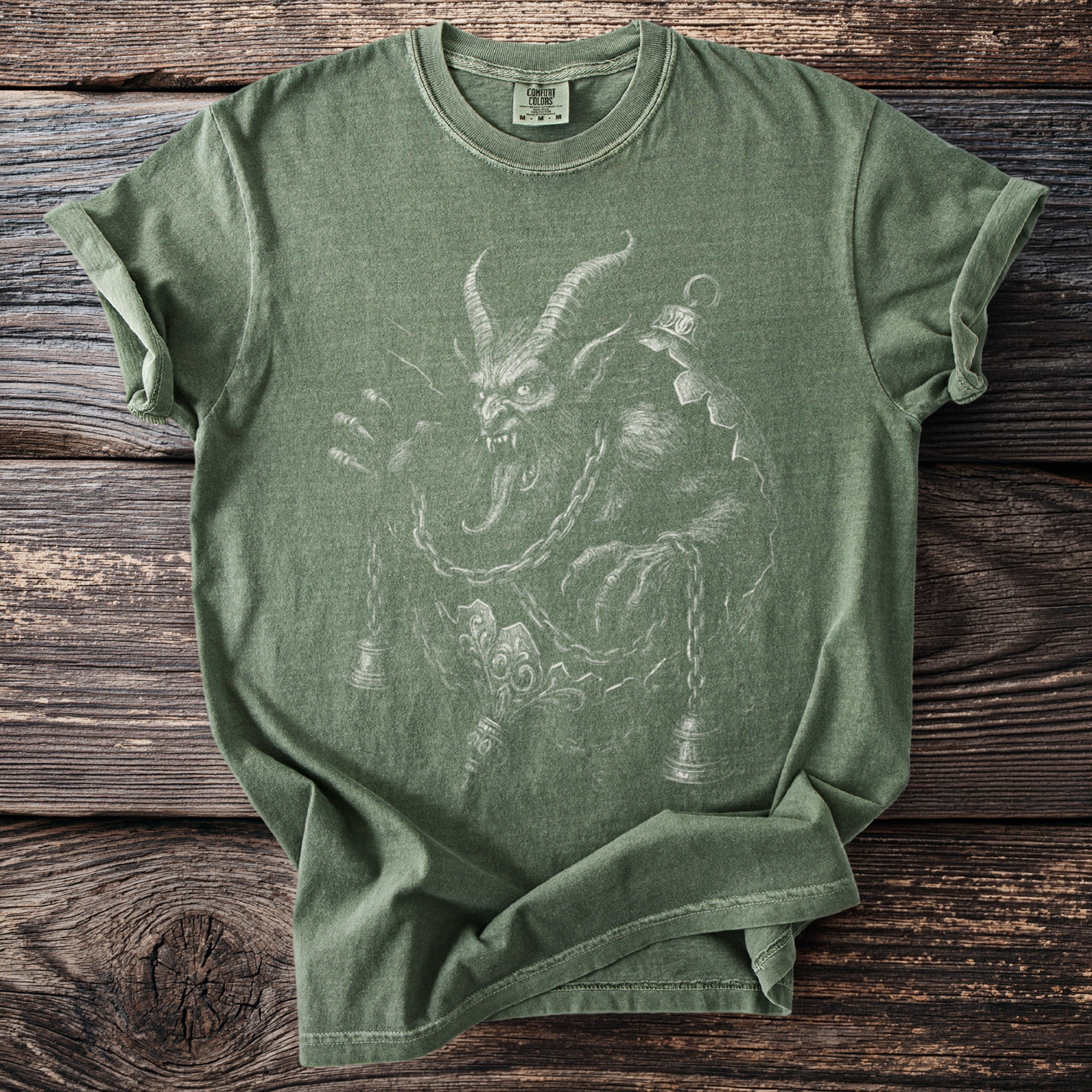 Green t-shirt featuring a graphic of a horned, fanged creature with chains and bells.