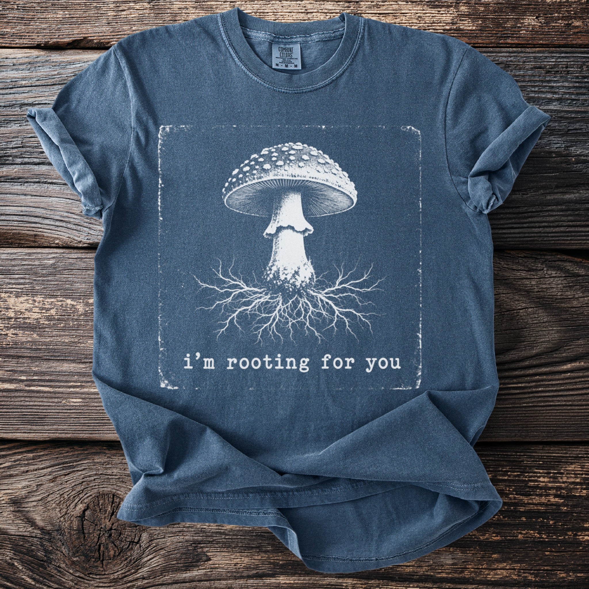 Blue t-shirt with a white mushroom illustration and text "i'm rooting for you".