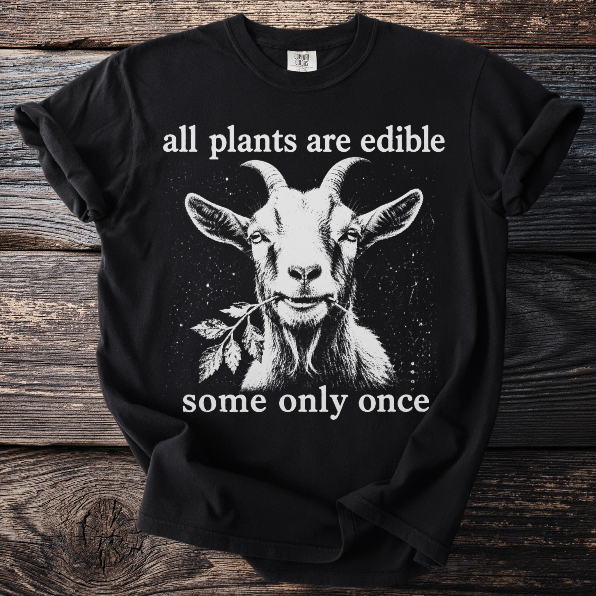 Black t-shirt with white goat eating a branch, text "all plants are edible some only once".