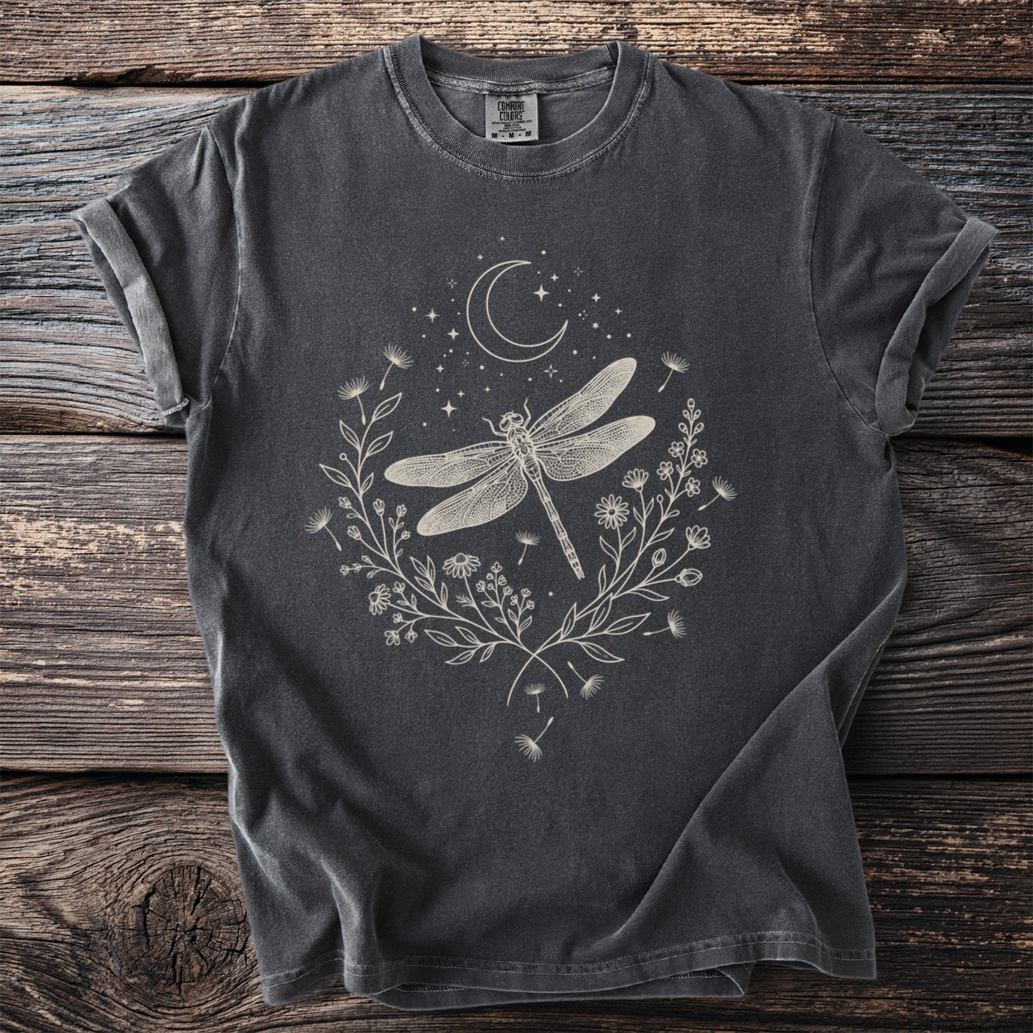 Dark grey t-shirt with a pale graphic of a dragonfly, crescent moon, stars, and floral wreath.