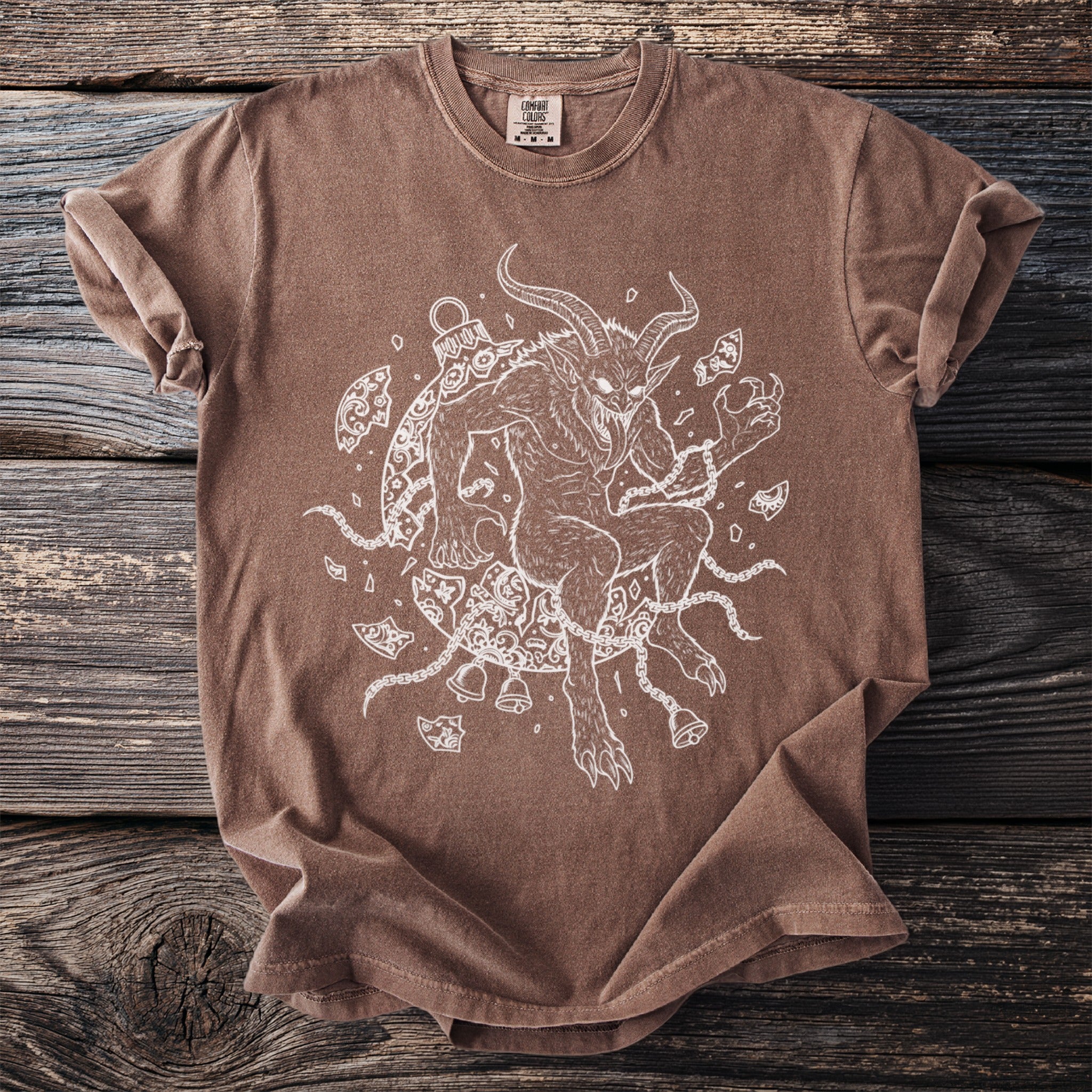 Brown t-shirt featuring a white line-art drawing of Krampus surrounded by chains and bells.