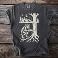 Pepper gray t-shirt with a cream folk-cut print: a horned goblin with a hand saw cuts into the trunk of a huge tree, its roots spread below.