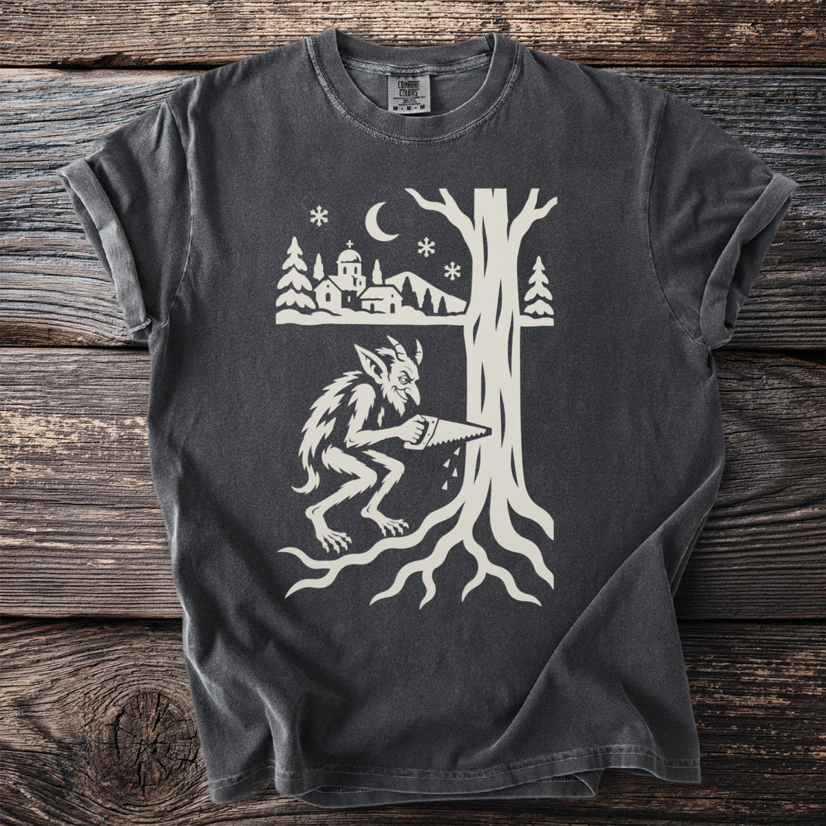 Pepper gray t-shirt with a cream folk-cut print: a horned goblin with a hand saw cuts into the trunk of a huge tree, its roots spread below.