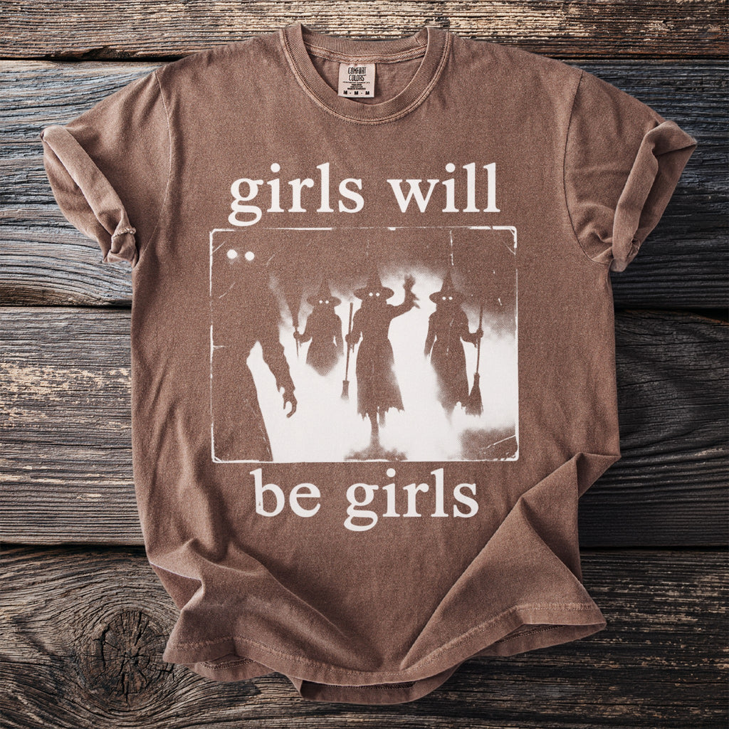 Brown t-shirt with glowing-eyed witches graphic and text "girls will be girls".