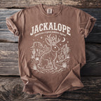 Brown t-shirt with a white graphic of a jackalope in a desert landscape.