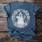 Blue t-shirt with circle design of a witch, book, herbs, and potions.