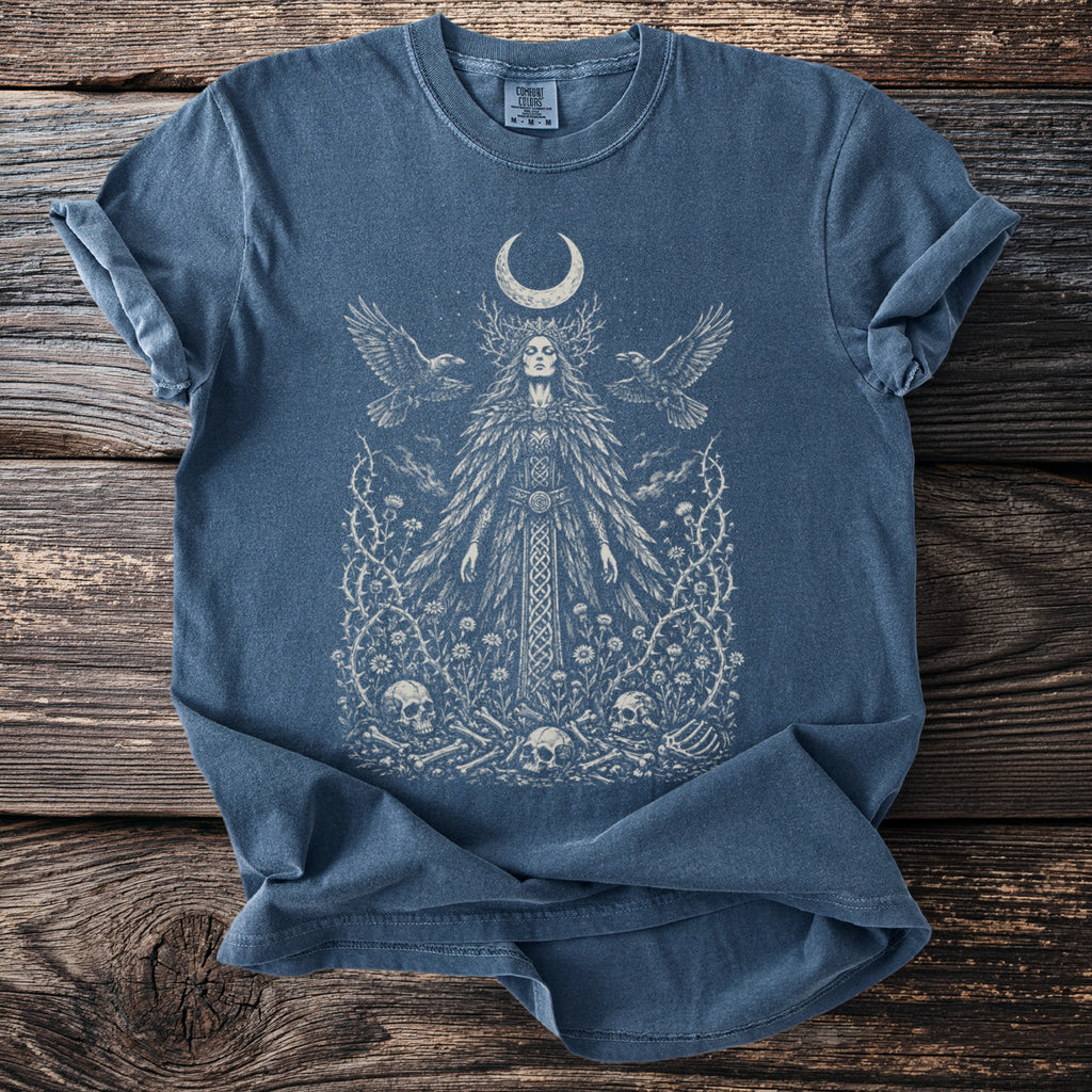 Blue t-shirt with mystical woman, moon, birds, skulls, and thorny vines graphic.