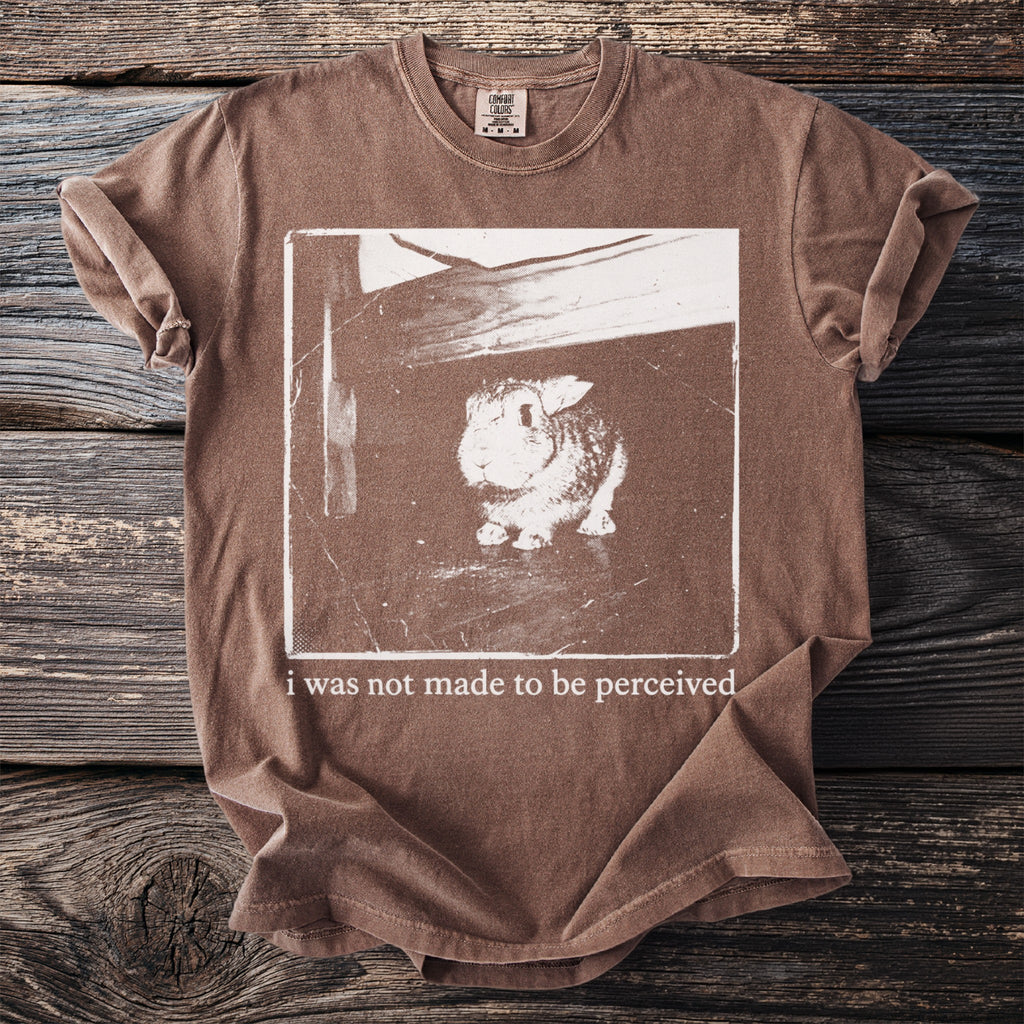 Brown t-shirt with a sepia-toned image of a rabbit and text "i was not made to be perceived."
