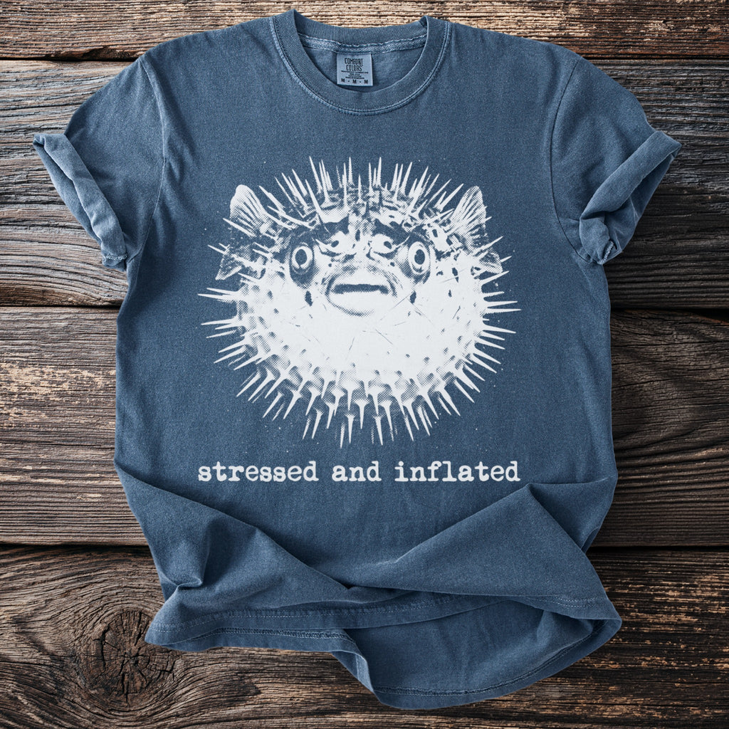 Blue t-shirt with a graphic of a pufferfish and the text "stressed and inflated."