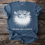 Blue t-shirt with a graphic of a pufferfish and the text "stressed and inflated."