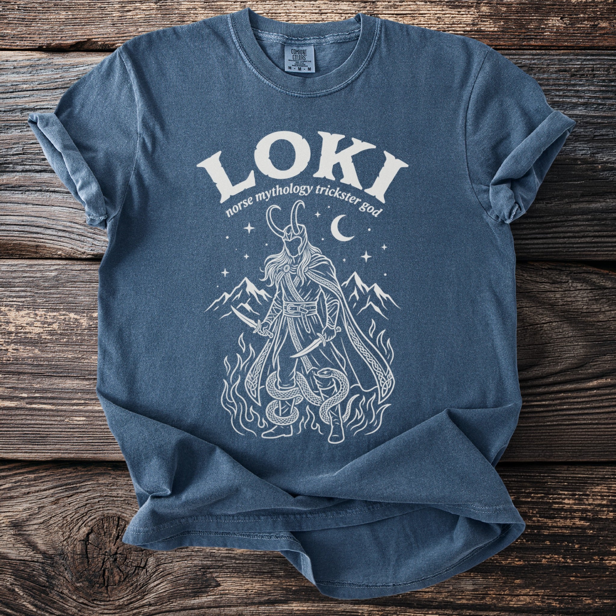 Blue t-shirt with white graphic of Loki, knives, and serpents.