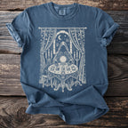 Blue t-shirt with white occult-themed graphic of a figure reading tarot cards and a crystal ball.
