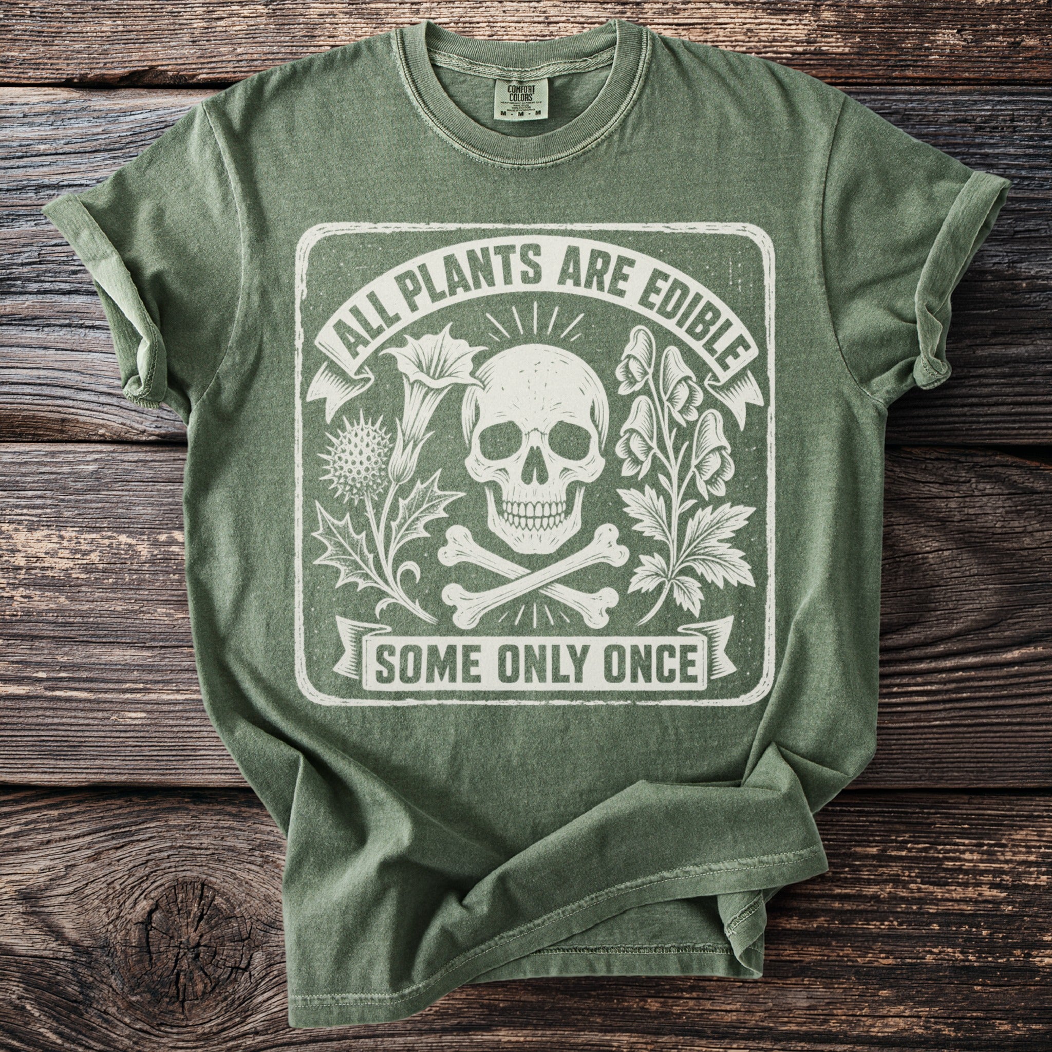 Green t-shirt with skull, crossbones, plants, and text that reads "ALL PLANTS ARE EDIBLE SOME ONLY ONCE."