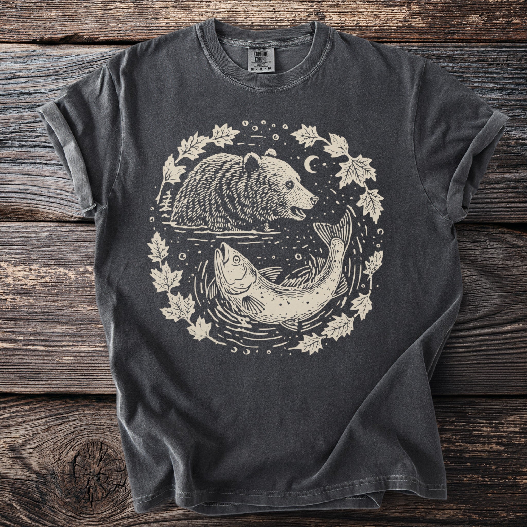 Dark gray t-shirt with circular graphic of a bear and fish with leaves and moon.