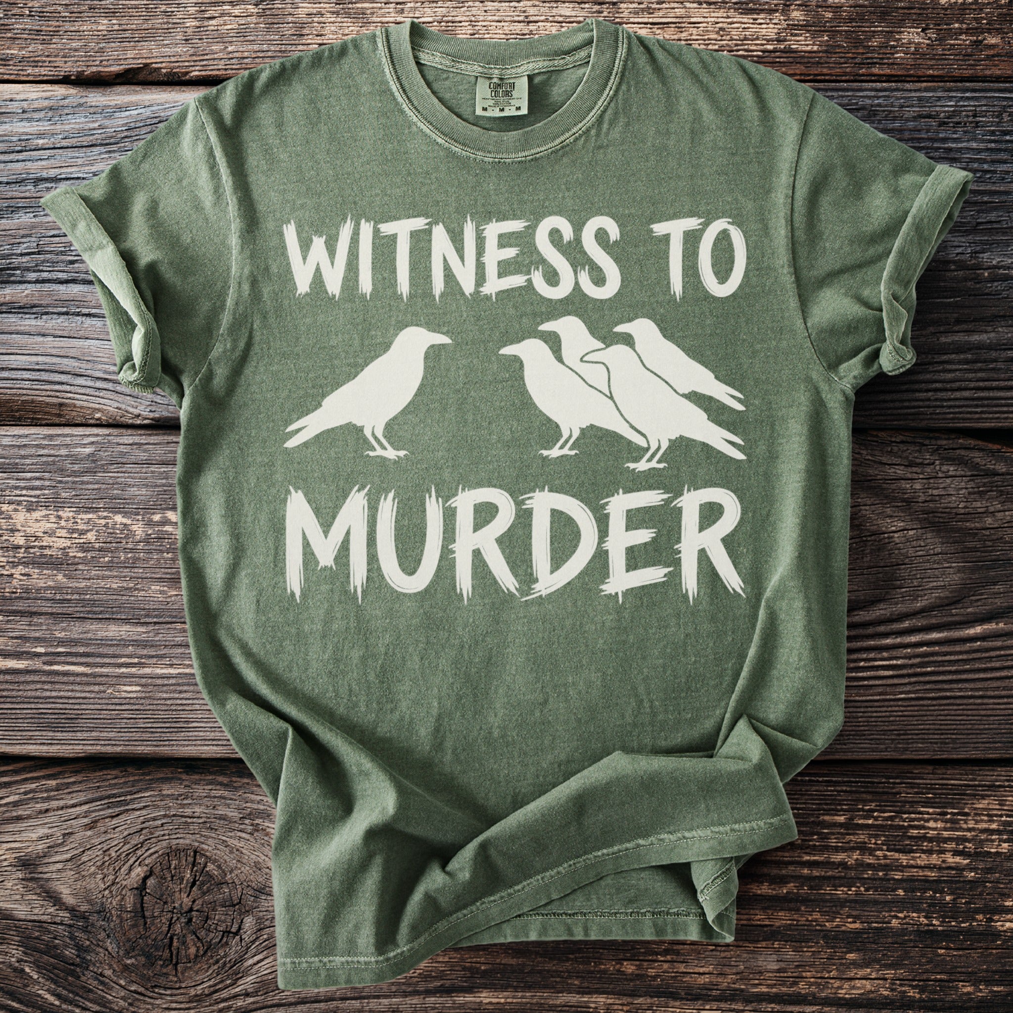 Green t-shirt with white text "WITNESS TO MURDER" and silhouette of crows.