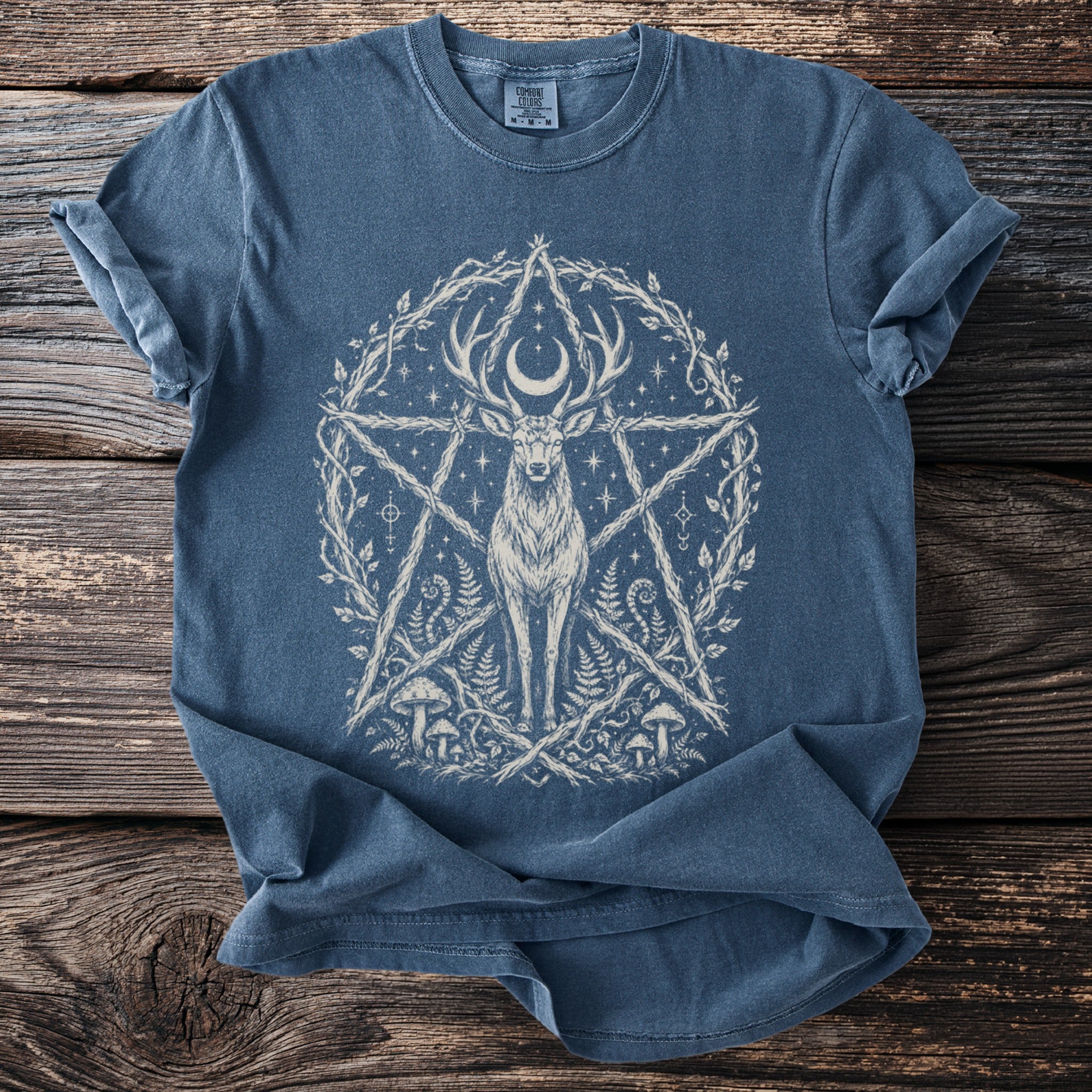 Blue t-shirt with a white deer, crescent moon, pentagram, and botanical elements.