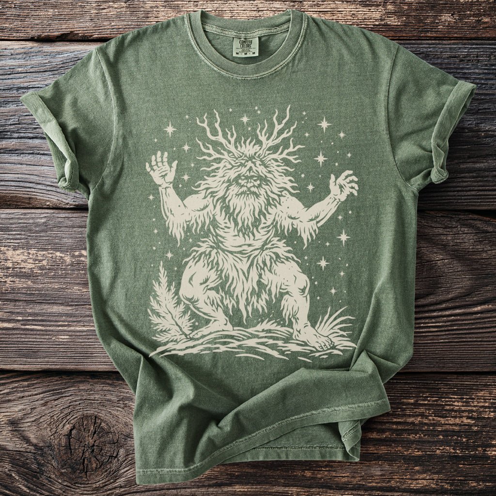 Green t-shirt with a cream graphic of a leafy, bearded creature with antlers and stars.