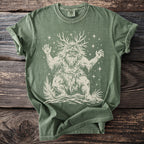 Green t-shirt with a cream graphic of a leafy, bearded creature with antlers and stars.