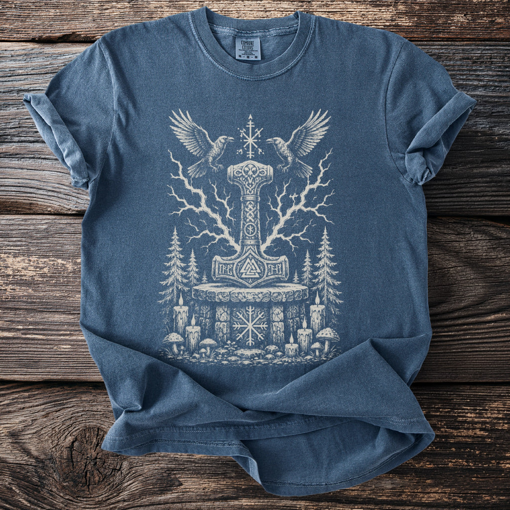 Blue t-shirt with a white Thor's hammer, runes, crows, trees, and candles graphic.