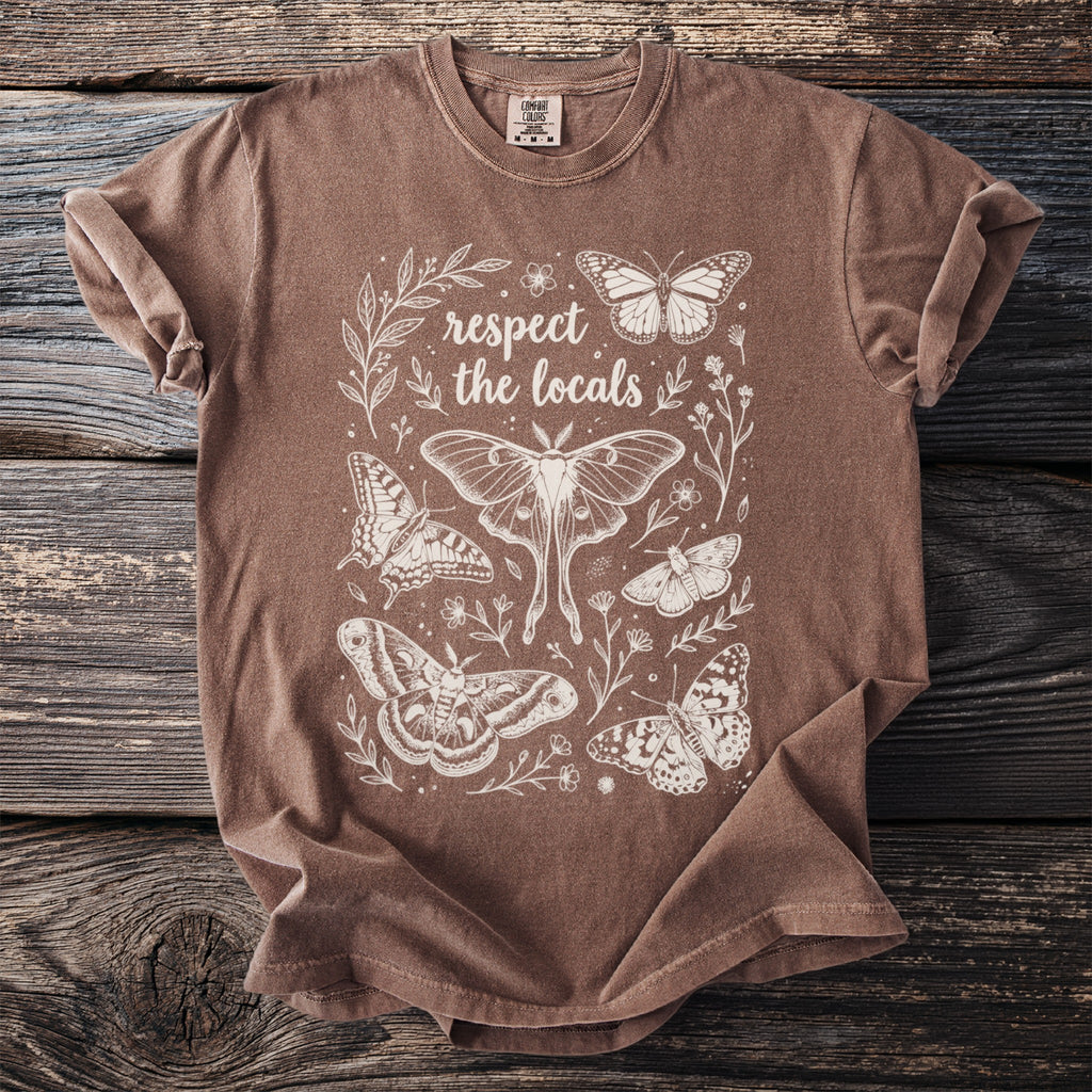 Brown t-shirt with white line art of butterflies, moths, leaves, and text "respect the locals".