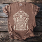 Brown t-shirt with a cream-colored occult graphic of a seated goat-headed figure.