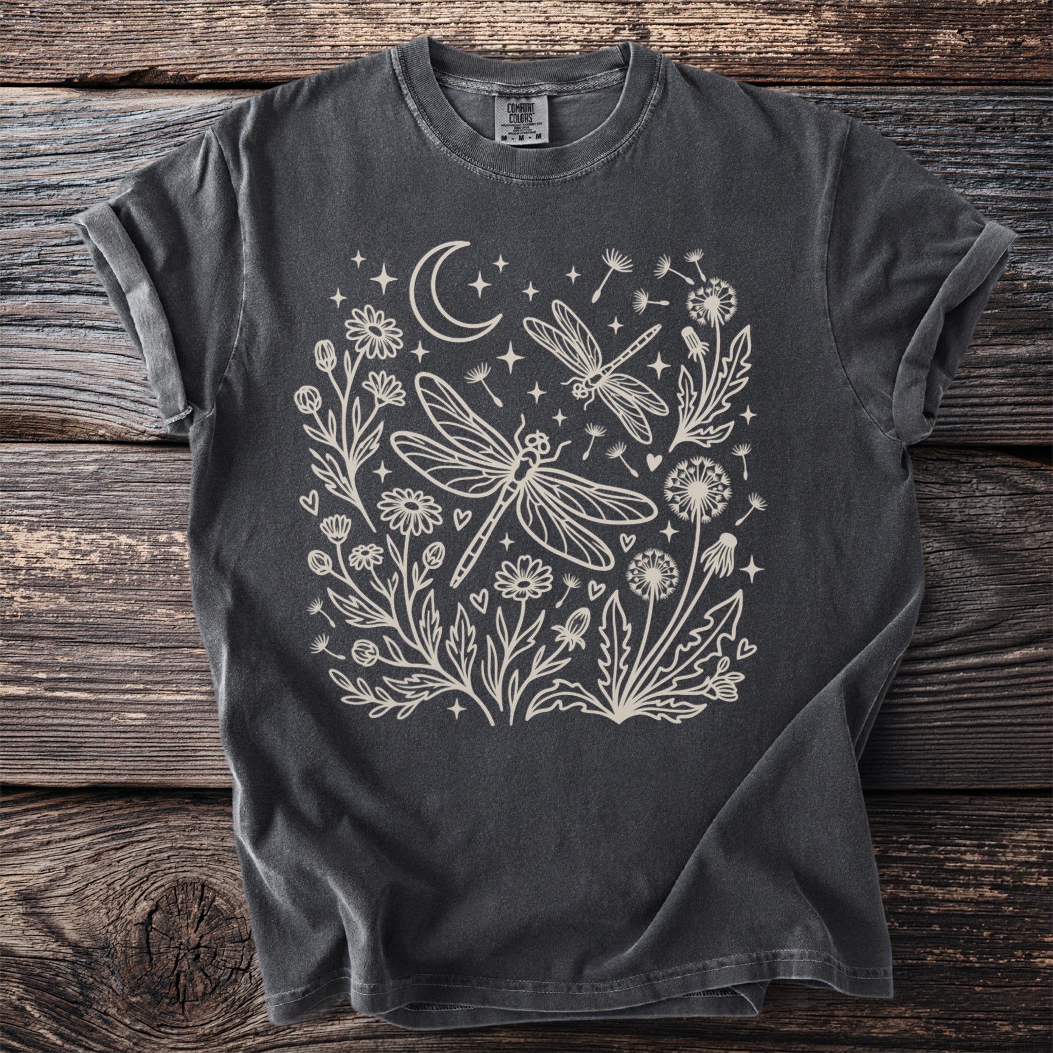 Dark grey t-shirt with outline design of dragonflies, flowers, crescent moon, and stars.