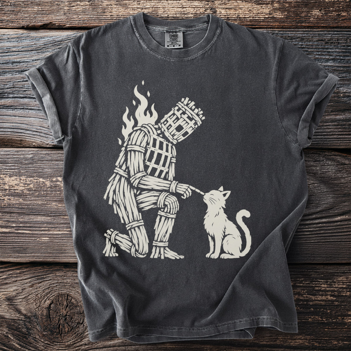 Dark gray t-shirt with a cream illustration of a wicker man kneeling to a cat.