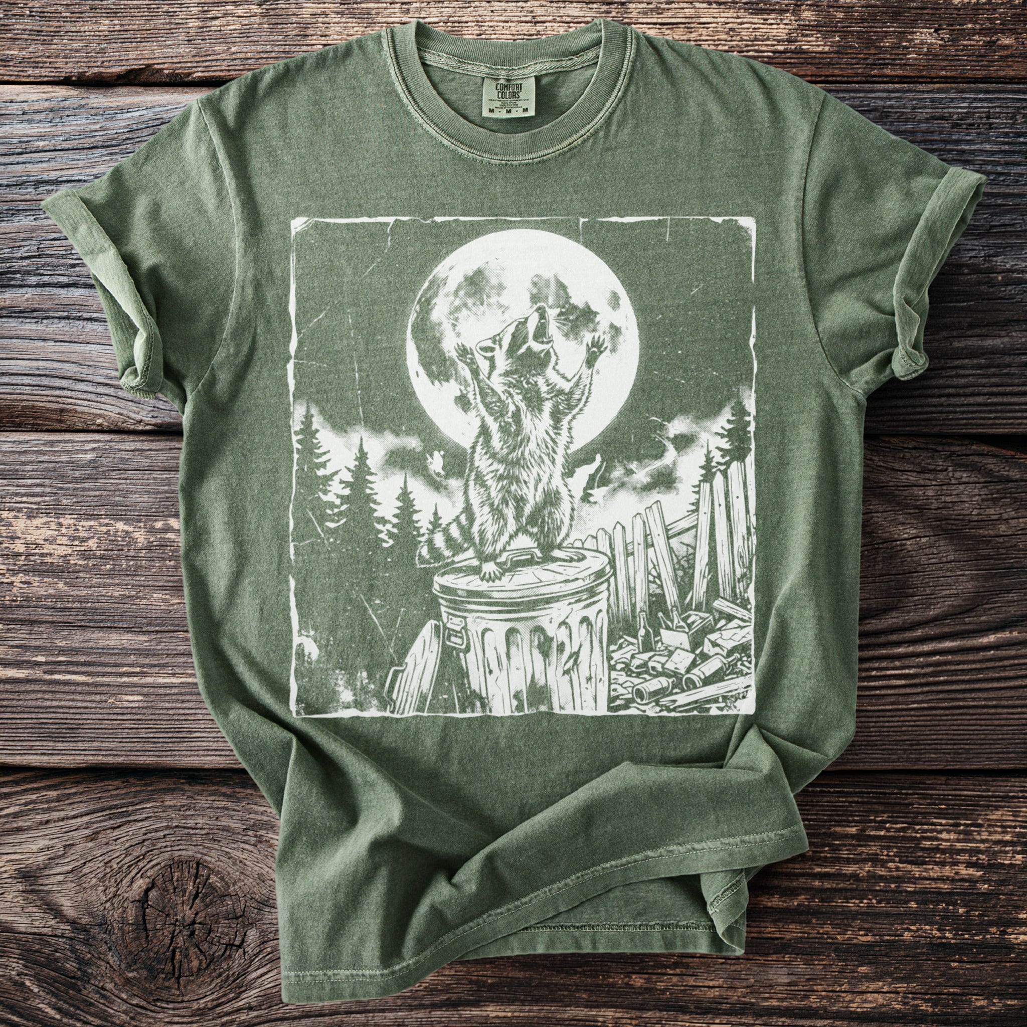 Green t-shirt with a distressed print of a raccoon howling at a full moon.