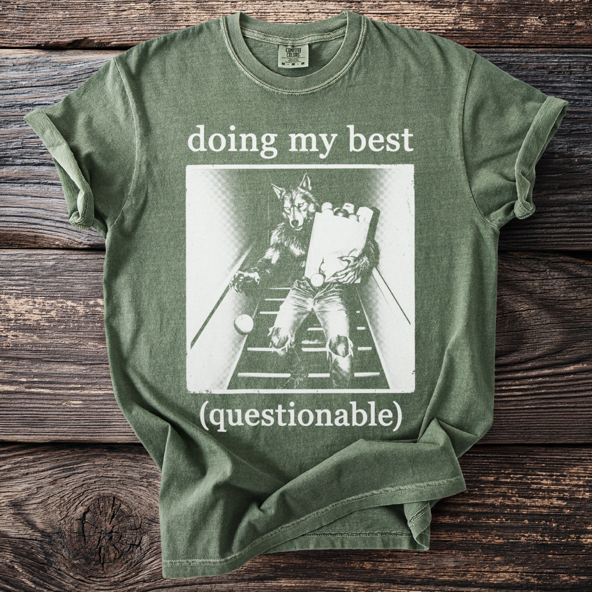 Green t-shirt with "doing my best (questionable)" and image of wolf carrying groceries.