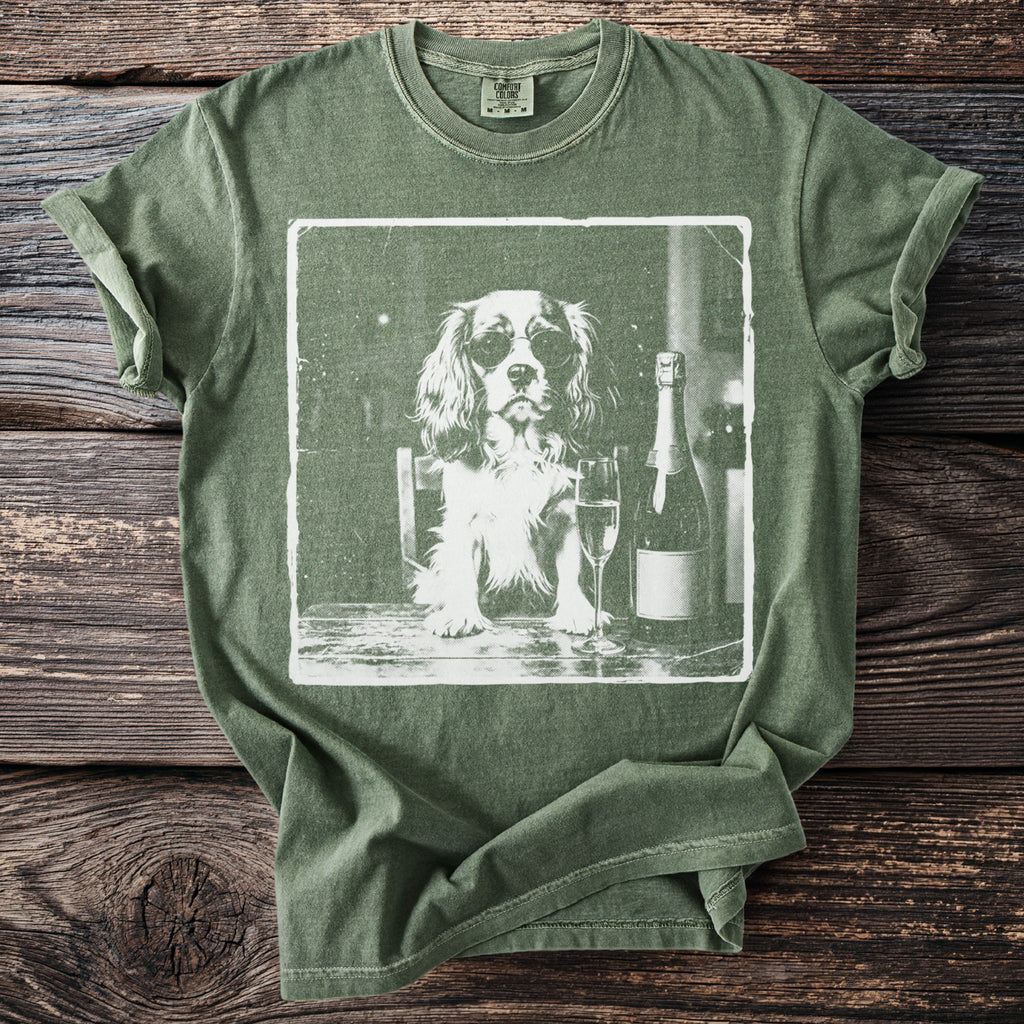 Green t-shirt with a graphic of a dog wearing sunglasses next to champagne.