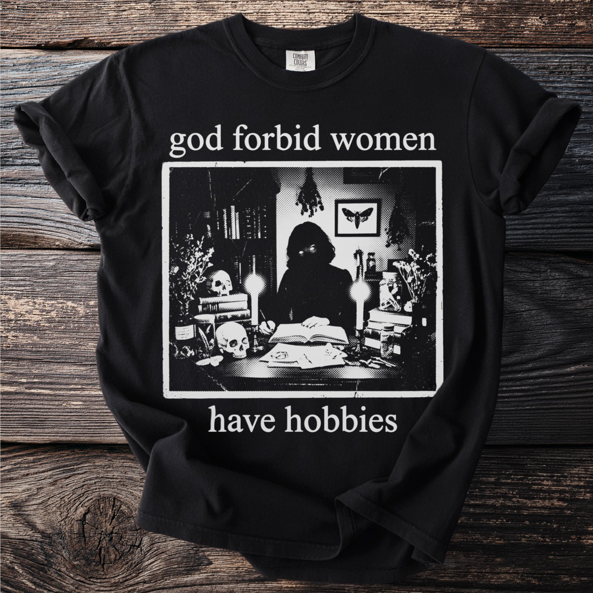 Black t-shirt with "god forbid women have hobbies" text and occult-themed graphic.