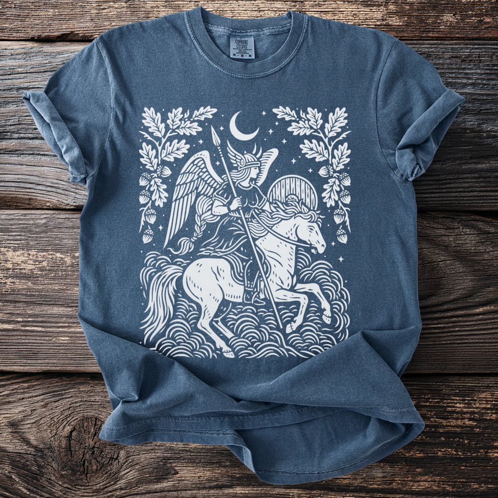 White illustration on blue t-shirt of winged rider on horse under moon and oak branches.
