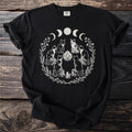 Black t-shirt with a circular design of cats, crystals, moons, and foliage.