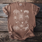 Brown t-shirt with a white line art graphic of various spiders and a scorpion.