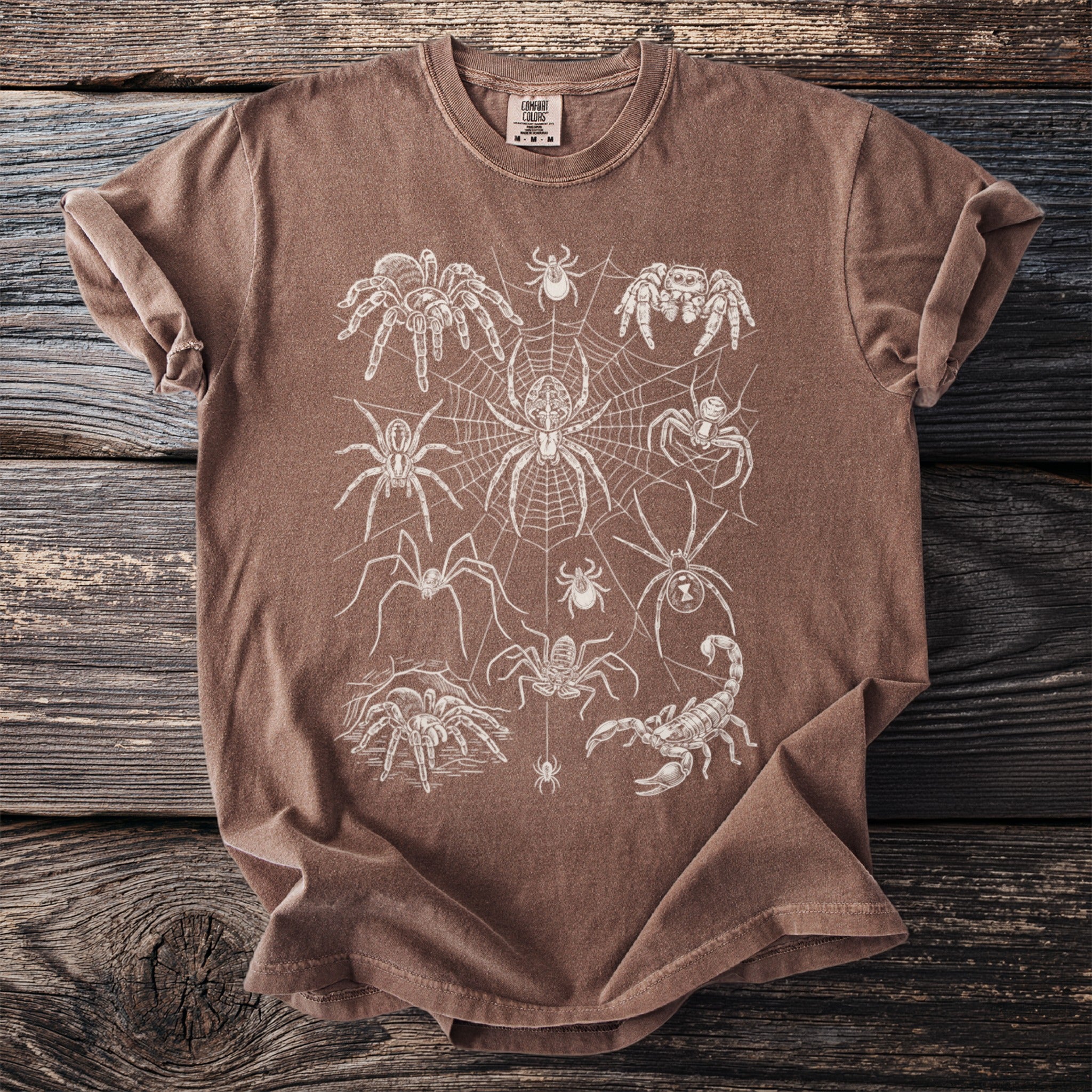 Brown t-shirt with a white line art graphic of various spiders and a scorpion.