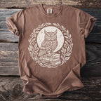 Brown t-shirt with a white illustration of an owl on stacked books within a leafy wreath.
