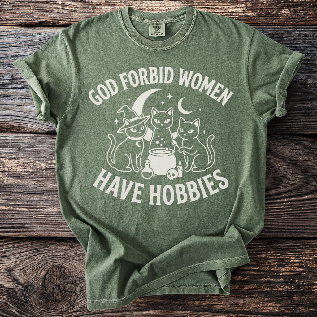Green t-shirt with white text and graphic of three cats around a cauldron.