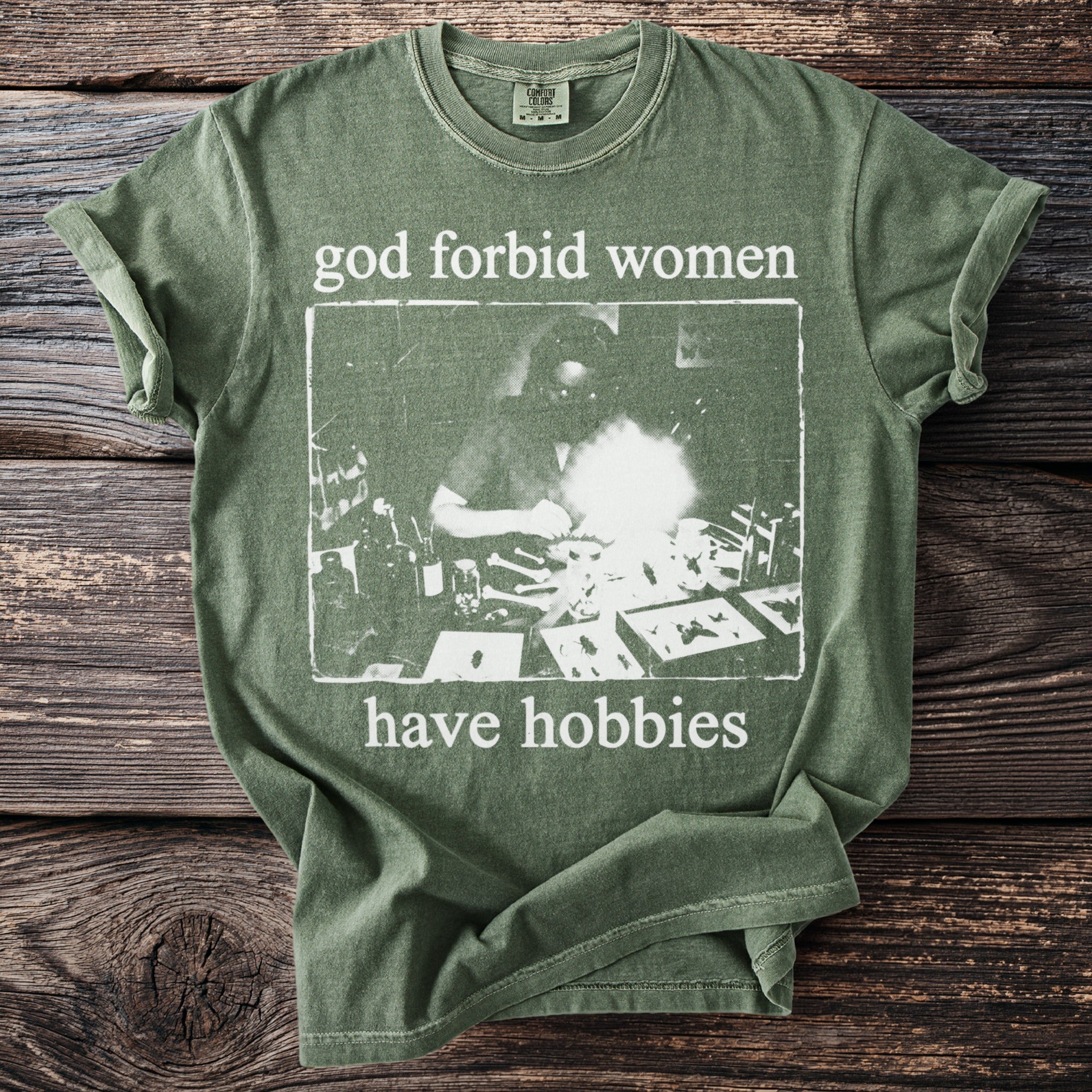 Green t-shirt with white text "god forbid women have hobbies" and a vintage graphic.