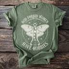 Green t-shirt with moth graphic and text "God Forbid Women Have Hobbies".