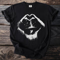 Black t-shirt with white distressed graphic of a person in a hat making a heart symbol with stars.