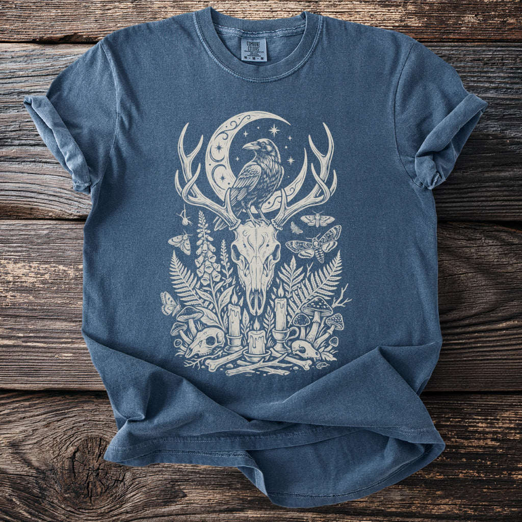 Blue t-shirt with cream occult-themed print featuring a raven, deer skull, moon, and flora.