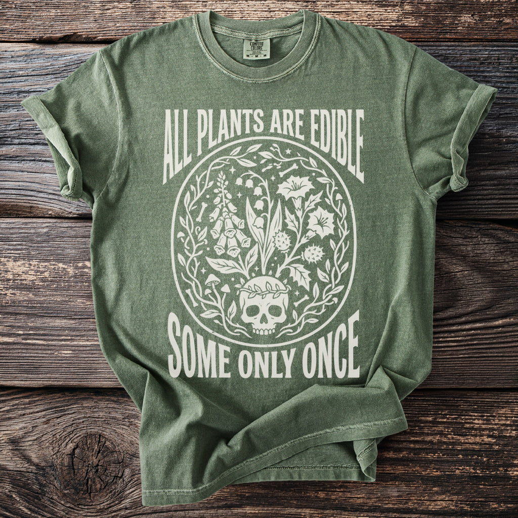 Green t-shirt with white text and illustration of a skull surrounded by plants.