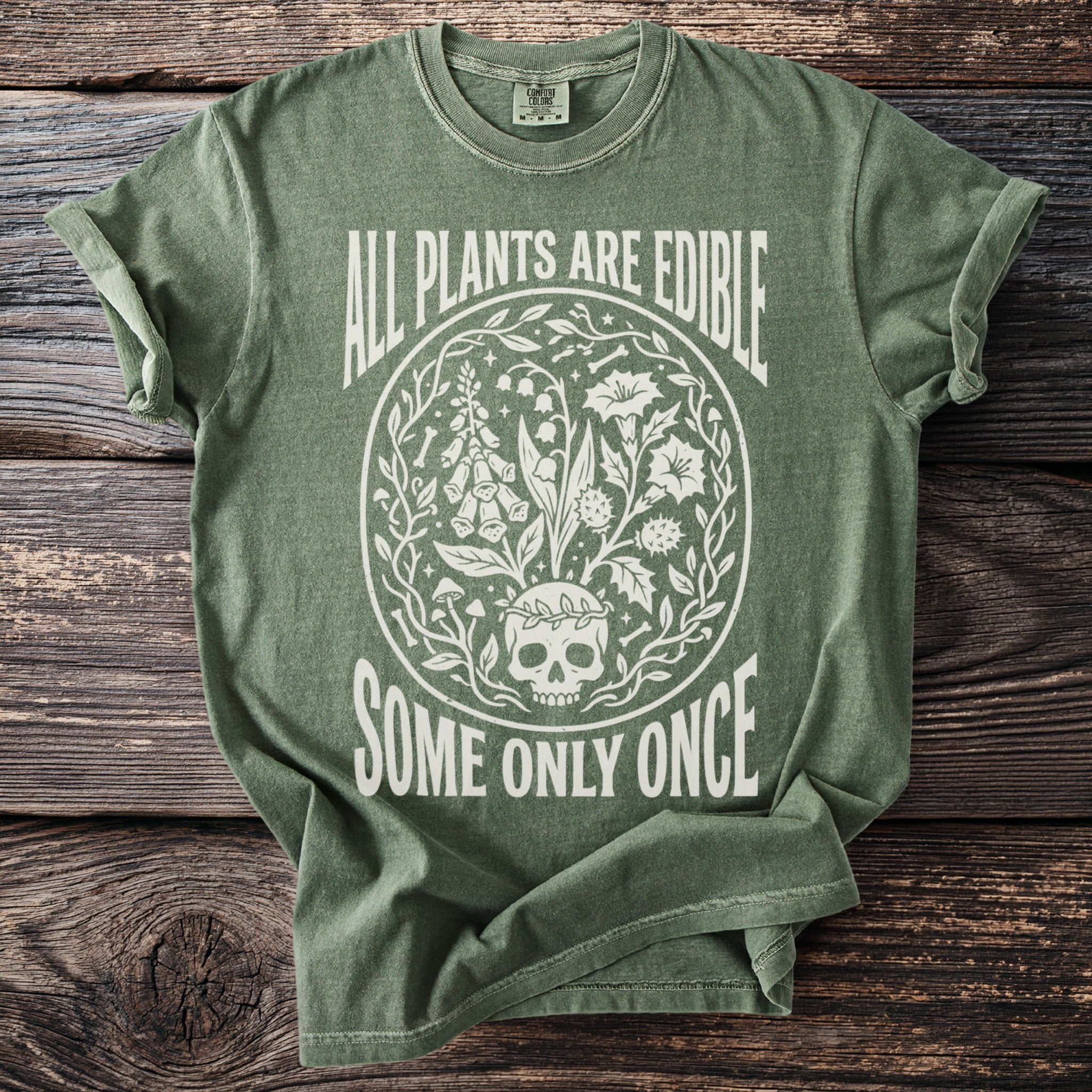 Green t-shirt with white text and illustration of a skull surrounded by plants.